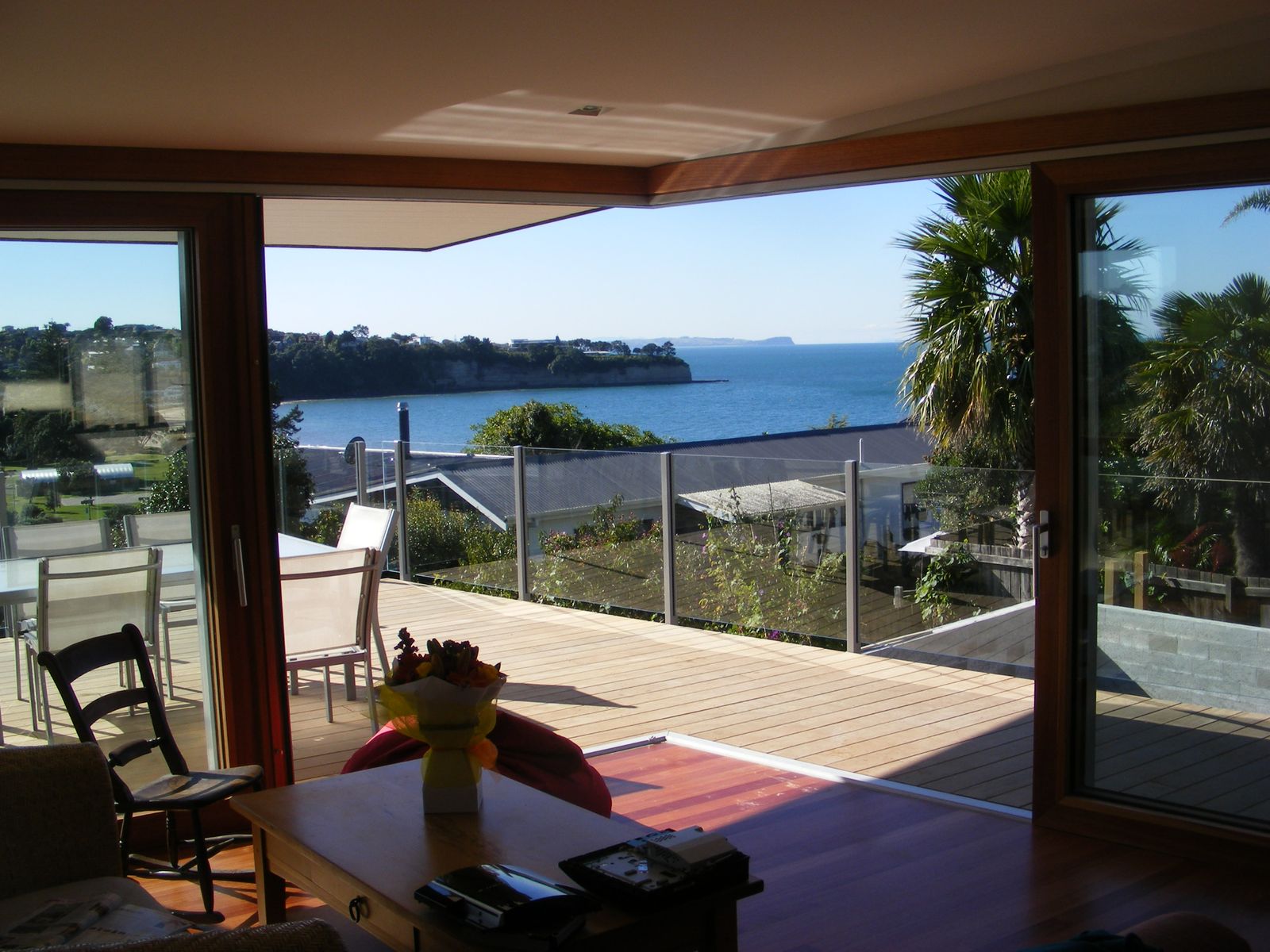 Wide sliding doors open to a timber deck with a sea view