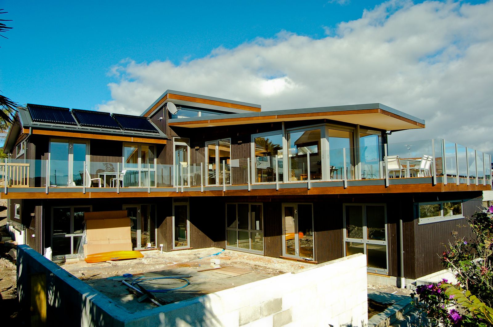 Timber clad home with solar panels on the roof and decks on two levels