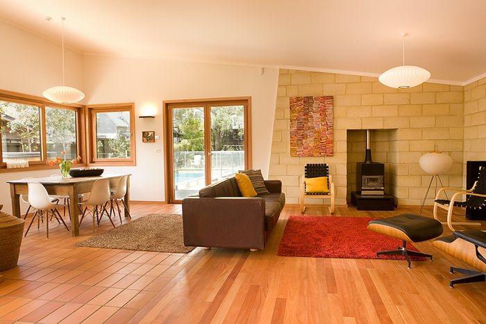 Living room with a wood burner, stone feature wall and timber floor