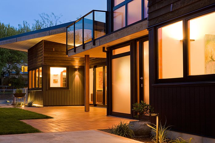 Timber clad exterior lit up at dusk with a glass balustrade above