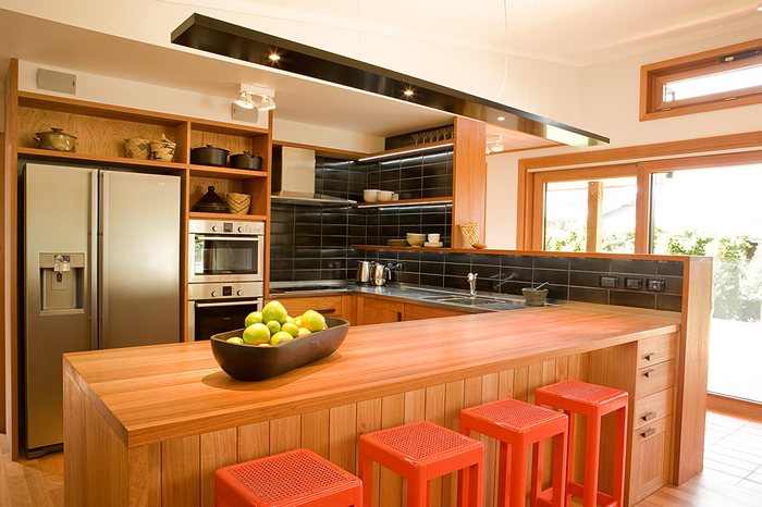 Kitchen with a timber island bench and orange stools